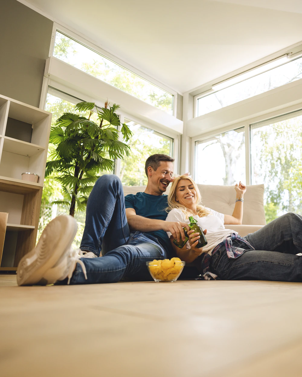 Paar sitzt im hellen, leeren Wohnzimmer seines neuen Zuhauses
