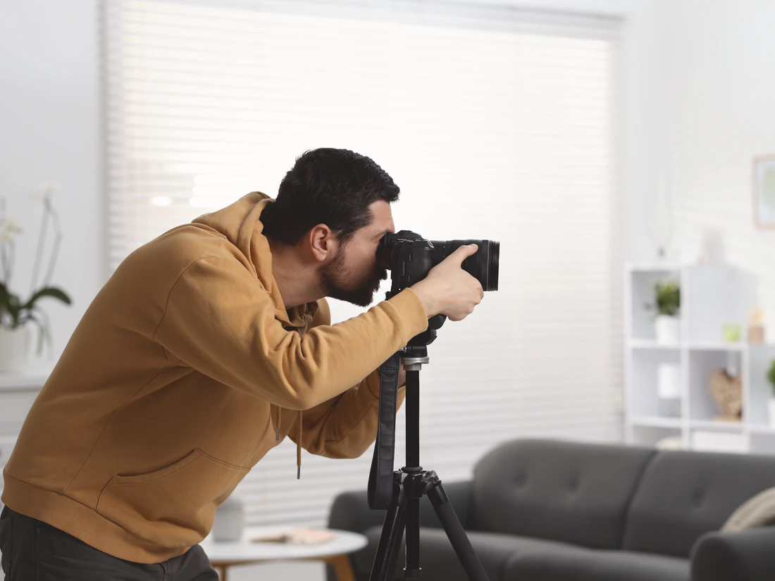 Fotograf fotografiert ein Wohnzimmer mit Kamera und Stativ